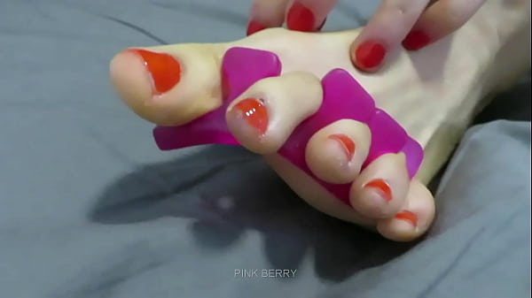 Aplicación de esmalte de uñas rojo en los pies.